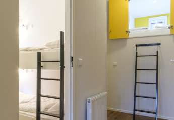 Binnenzicht van de Vechtdallodge bij Kampeerdorp de Zandstuve in Nederland, met stapelbedden en ladder.