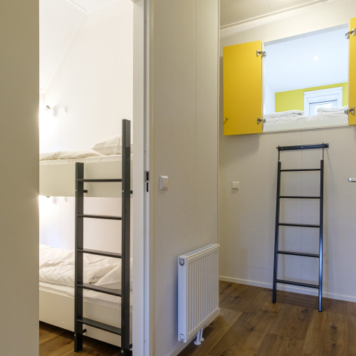 Interieur van de Vechtdallodge op Kampeerdorp de Zandstuve in Nederland, met stapelbedden en een ladder.