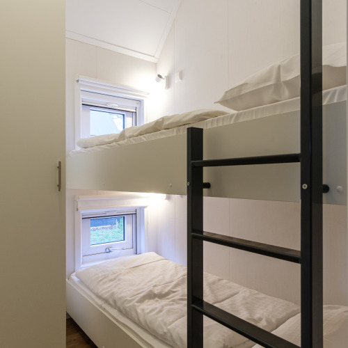 Moderne stapelbedden en ramen in een lichte lodge bij Vechtdallodge, Kampeerdorp de Zandstuve, Nederland.