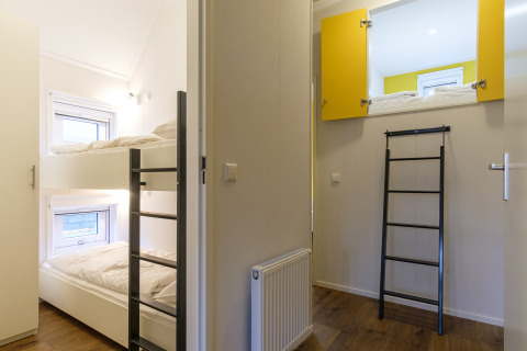 Habitación con literas y cama en altillo con escalera en Vechtdallodge, Kampeerdorp de Zandstuve, Países Bajos.