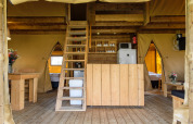 Innenraum des Safari-Zelts Verandalodge im Kampeerdorp de Zandstuve mit Holzmöbeln und Dachboden.