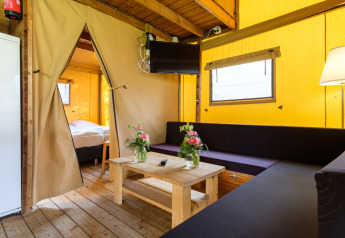 Vue intérieure d'une tente safari Verandalodge chaleureuse avec salon et chambre à Kampeerdorp de Zandstuve, Pays-Bas.