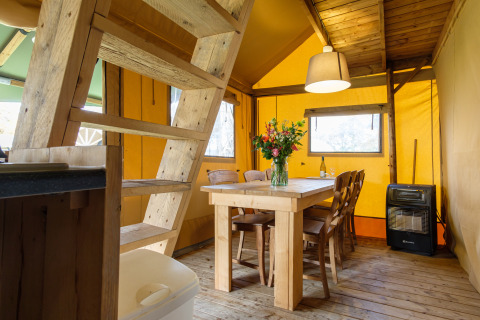 Interior de la tienda safari Verandalodge con mesa y sillas de madera en Kampeerdorp de Zandstuve, Países Bajos.