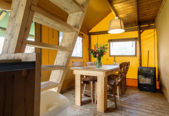 Interno della tenda safari Verandalodge con tavolo e sedie in legno al Kampeerdorp de Zandstuve, Paesi Bassi.