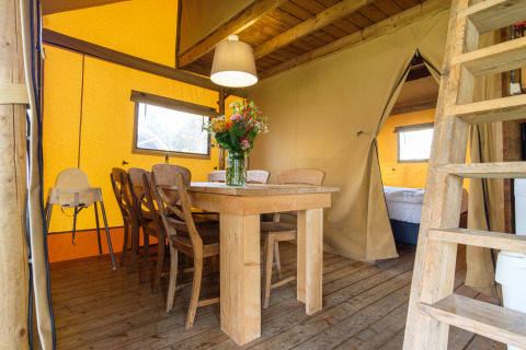 Indvendigt billede af Verandalodge safari-telt med spisebord og stole i Kampeerdorp de Zandstuve.