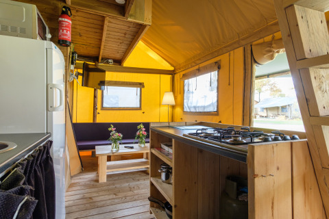 Vue intérieure de la tente safari Verandalodge à Kampeerdorp de Zandstuve, avec cuisine et coin salon.