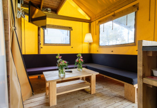 Innenansicht eines Verandalodge-Safarizeltes mit Holzmöbeln und komfortabler Einrichtung in den Niederlanden.