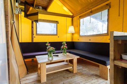 Intérieur d'une tente safari Verandalodge avec mobilier en bois et ambiance chaleureuse, aux Pays-Bas.