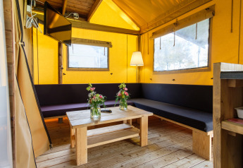 Intérieur d'une tente safari Verandalodge avec mobilier en bois et ambiance chaleureuse, aux Pays-Bas.