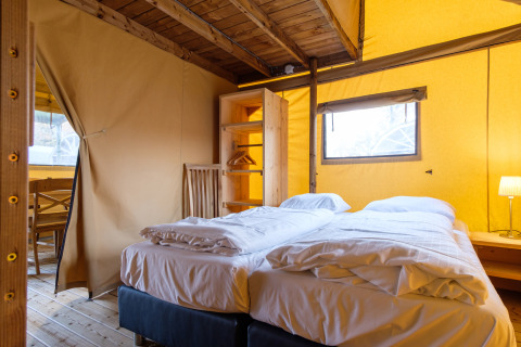 Vista interior de una cómoda tienda safari Verandalodge con cama doble en Kampeerdorp de Zandstuve, Países Bajos.