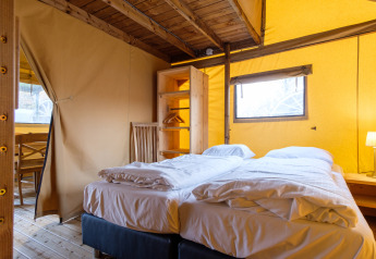 Vista interna di una confortevole tenda safari Verandalodge con letto matrimoniale a Kampeerdorp de Zandstuve, Paesi Bassi.