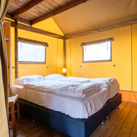 Letto confortevole in una tenda safari Verandalodge a Kampeerdorp de Zandstuve, Paesi Bassi, pavimento in legno.