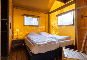 Camera da letto nella tenda safari Verandalodge a Kampeerdorp de Zandstuve, Paesi Bassi, con due letti.