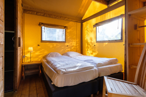Dormitorio en tienda safari Verandalodge en Kampeerdorp de Zandstuve, Países Bajos, con dos camas.