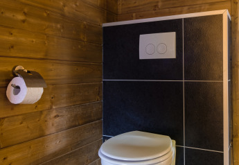 Moderno WC e porta carta igienica in un bagno rivestito in legno alla Verandalodge, Kampeerdorp de Zandstuve.