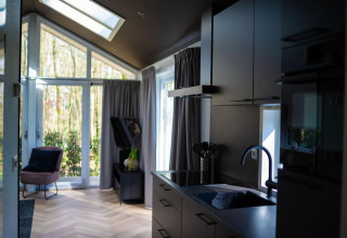 Interior luminoso y moderno de Bos Cottage en De Thijmse Berg, Países Bajos, con vistas al bosque por la ventana.