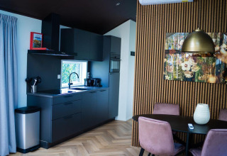 Cocina y comedor modernos en Bos Cottage, De Thijmse Berg, Países Bajos, con muebles negros y pared de madera.