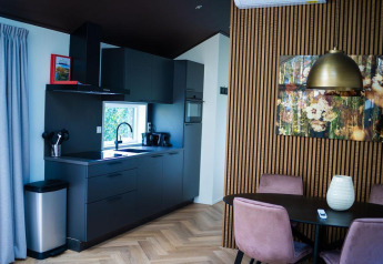 Moderne køkken- og spiseområde på Bos Cottage, De Thijmse Berg, med sort inventar og trævæg i Holland.