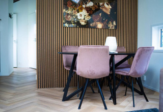 Comedor moderno con sillas rosas y mesa redonda en Bos Cottage, De Thijmse Berg, Países Bajos.
