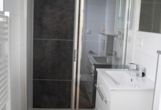 Modernes Badezimmer in der Bos Cottage in De Thijmse Berg, Niederlande, mit Dusche und Waschbecken.