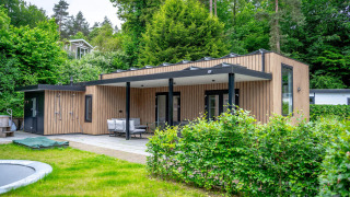 Wellness Cottage 6p a De Thijmse Berg nei Paesi Bassi, moderno lodge rivestito in legno in mezzo al verde.