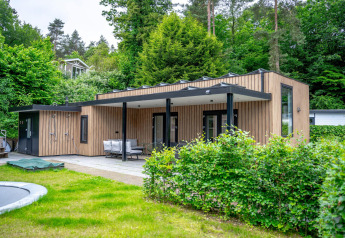 Wellness Cottage 6p bij De Thijmse Berg in Nederland, modern houten lodge in een groene, bosrijke omgeving.