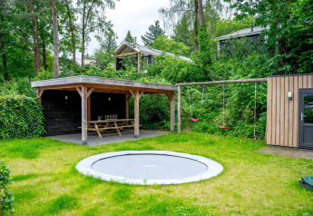 Kindvriendelijke tuin met ingegraven trampoline, schommels en overdekte picknickruimte bij Wellness Cottage 6p, De Thijmse Berg.