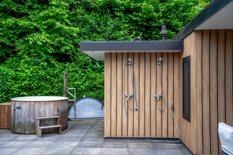 Udendørs wellnessområde med træbadekar og brusere ved Wellness Cottage 6p på De Thijmse Berg, Holland.