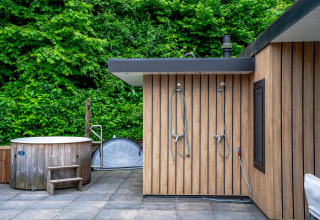 Udendørs wellnessområde med træbadekar og brusere ved Wellness Cottage 6p på De Thijmse Berg, Holland.