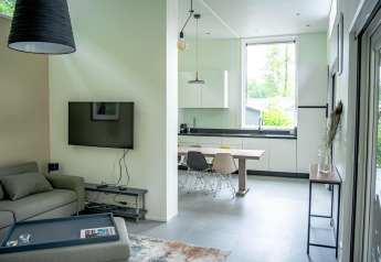 Moderne stue og køkken i Wellness Cottage 6p ved De Thijmse Berg, Holland. Store vinduer og stilfuldt interiør.