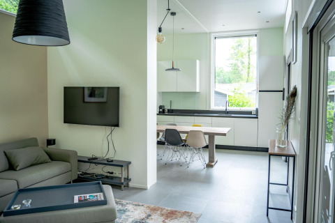 Soggiorno e cucina moderni al Wellness Cottage 6p presso De Thijmse Berg, Paesi Bassi, con ampia finestra e arredo chic.