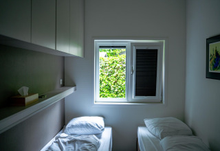 Dormitorio pequeño con dos camas individuales y ventana, Wellness Cottage 6p, De Thijmse Berg, Países Bajos.