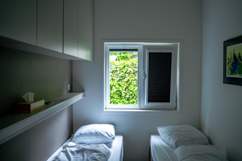 Piccola camera da letto con due letti singoli e finestra, Wellness Cottage 6p, De Thijmse Berg, Paesi Bassi.