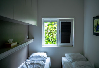 Piccola camera da letto con due letti singoli e finestra, Wellness Cottage 6p, De Thijmse Berg, Paesi Bassi.