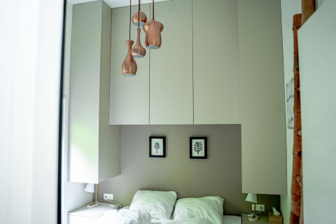 Modern bedroom with sleek white cabinets, unique pendant lights, and a cozy double bed at Wellness Cottage 6p.