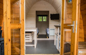 Eingang zu einer Pod-Hütte mit Holzwänden, Betten und TV im Kampeerdorp de Zandstuve, Niederlande.