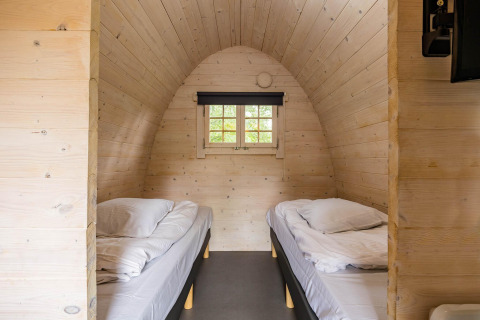 Innenansicht einer gemütlichen Holz-Pod mit zwei Einzelbetten bei Kampeerdorp de Zandstuve, Niederlande.