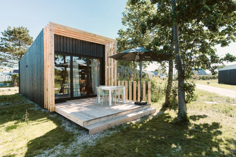 Modernes Tiny House Klaproos mit Holzterrasse und Gartenmöbeln im Ferienpark De Klepperstee, Niederlande.