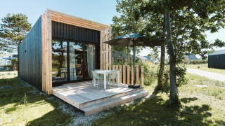 Moderne tiny house Klaproos med træterrasse og havemøbler på ferieparken De Klepperstee i Holland.