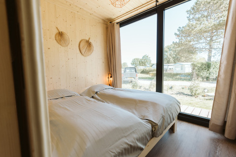 Bedroom with two single beds and large windows in a tiny house at Holiday park De Klepperstee, Netherlands.