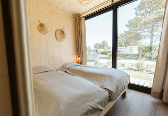Camera con due letti singoli e grandi finestre in una tiny house nel parco vacanze De Klepperstee, Paesi Bassi.