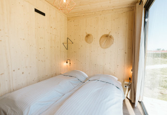 Dormitorio en la tiny house Klaproos en el parque vacacional De Klepperstee, Países Bajos, con dos camas.