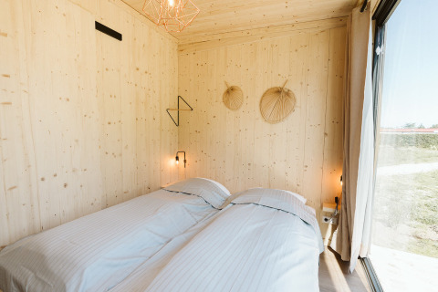 Camera da letto nella tiny house Klaproos al parco vacanze De Klepperstee, Paesi Bassi, con due letti singoli.