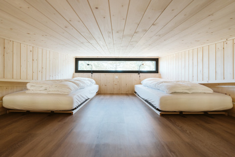 Dormitorio minimalista con dos camas individuales en el tiny house Klaproos, De Klepperstee, Países Bajos.