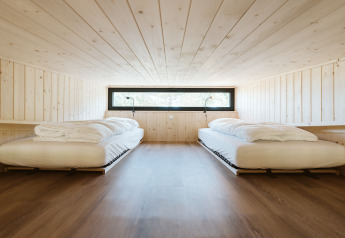 Dormitorio minimalista con dos camas individuales en el tiny house Klaproos, De Klepperstee, Países Bajos.