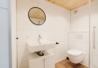 Moderne badeværelse i en tiny house ved Holiday park De Klepperstee, Nederlandene, med træloft og rund spejl.