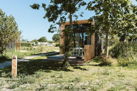 Klaproos tiny house ved Holiday park De Klepperstee i Holland omgivet af grønne træer og en have.