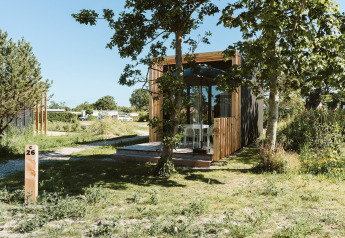 Klaproos tiny house at Holiday park De Klepperstee in the Netherlands, surrounded by trees and greenery.