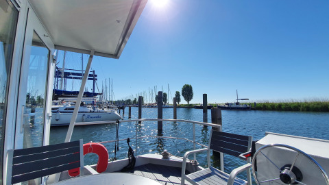 Vista desde la casa flotante Havenlodge Lelystad en Marina Parcs con yates y cielo soleado en los Países Bajos.