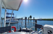 Vista desde la casa flotante Havenlodge Lelystad en Marina Parcs con yates y cielo soleado en los Países Bajos.